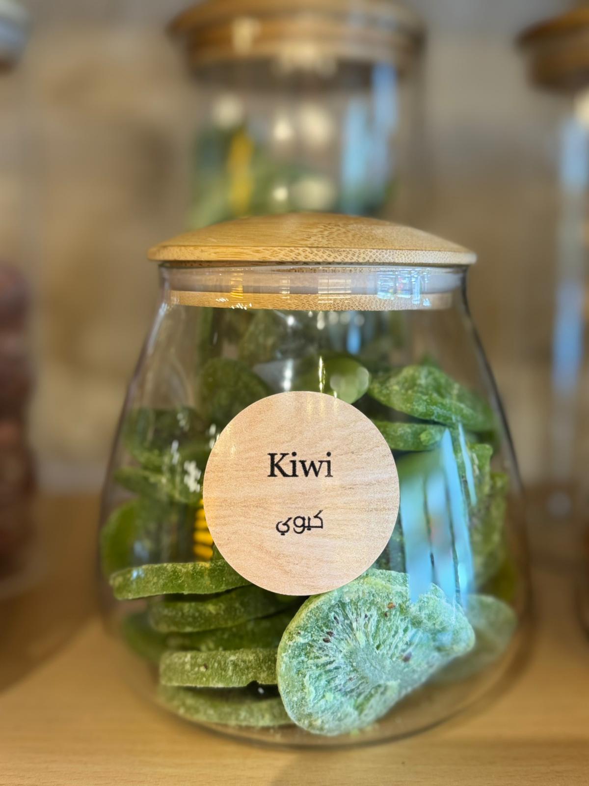 Glass jar with wooden lid and label indicating 'Kiwi' on a wooden surface.