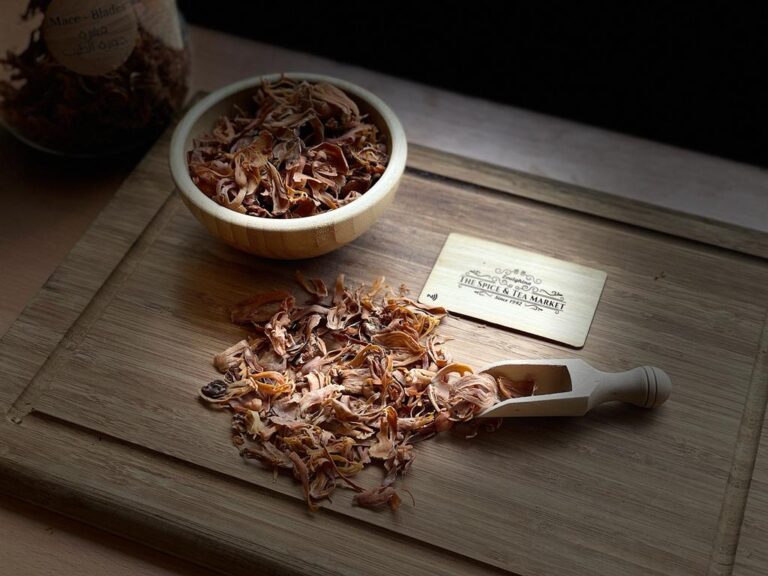 Mace blades on a wooden surface with a small scoop and a card.