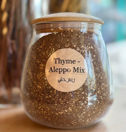 Glass jar with Thyme Aleppo Mix and wooden lid on a blurred background