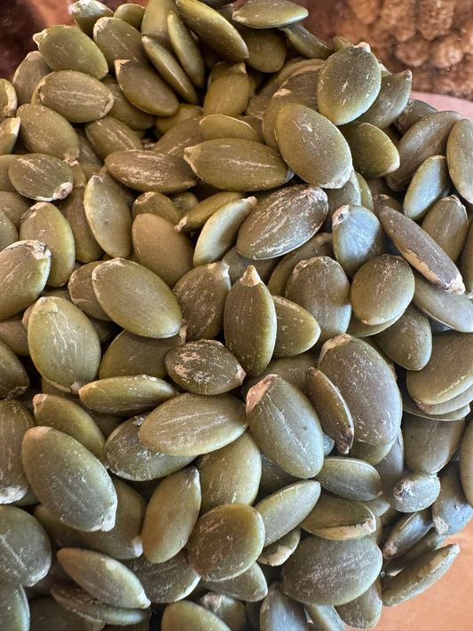 Close-up of green pumpkin seeds on a wooden surface