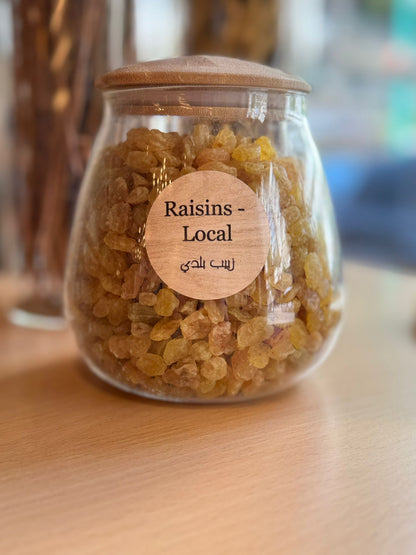 Glass jar with raisins and a wooden lid on a wooden surface