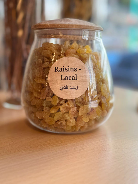Glass jar with raisins and a wooden lid on a wooden surface