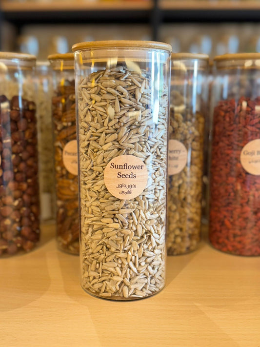 Glass jar labeled 'Sunflower Seeds' filled with sunflower seeds on a wooden surface.